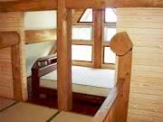畳が敷かれ、格子状の光がよく入る窓枠の近くにベッドがある部屋の写真