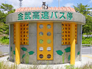オレンジ色と緑色を基調にした円柱形の外観の、金武高速バス停留所の写真